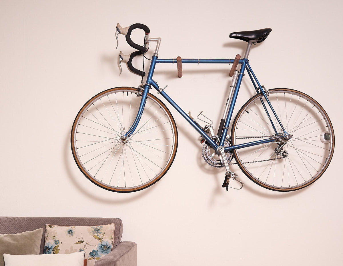 Blue bike on the smoked beech Bike Wall Hanger #3 on a white wall above a sofa